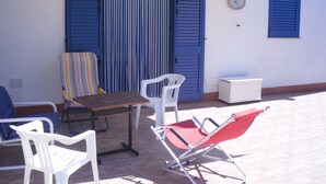 An outdoor seating area with a table and chairs, a striped chair, and a red folding chair. - NEAR THE SEA AND AWAY FROM NOISES (alcamo marina)