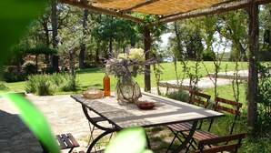 An outdoor patio with a table and chairs, surrounded by greenery and trees. - Poggio Corsucci.Panoramic mansion with swimming pool between Florence and Arezzo (Loro Ciuffenna (Province of Arezzo))