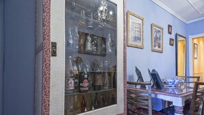 Una stanza con un mobile vetrina che espone diverse bottiglie, un tavolo da pranzo con sedie e quadri appesi alle pareti.