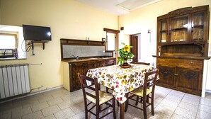 Un comedor con una mesa lista para dos personas, un mueble de madera y un televisor montado en la pared.