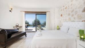 A bedroom with a large bed, a sofa, a small table with a lamp, and a view of the outdoors. - Luxury Kalkan Villa With 2 Pools and Guest House Perfect for Friends or Families (Kalkan)