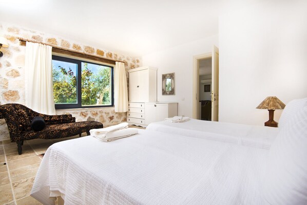 Une chambre avec un grand lit, un canapé, une commode et une fenêtre avec des rideaux.