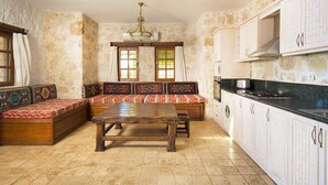 A traditional kitchen with stone walls, a wooden bench with patterned cushions, a dining table, and a stove. - Luxury Kalkan Villa With 2 Pools and Guest House Perfect for Friends or Families (Kalkan)