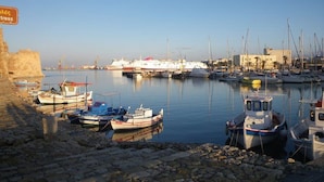 Uma marina com barcos atracados, um navio grande ao fundo e uma placa com a inscrição 'Hotel'.