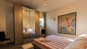 A hotel room with a bed, a chair, a bench, a wardrobe, a mirror, and a painting on the wall. - Exclusive Villa with private salt pool (Case Alte)