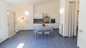 A compact kitchen with white cabinets, a stainless steel range hood, and a tiled floor. - Exclusive Villa with private salt pool (Case Alte)