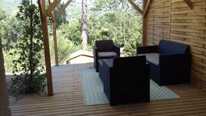 A wooden deck with wicker furniture and a patterned rug.