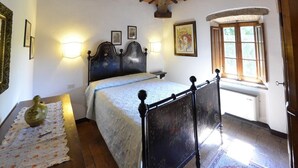 A bedroom with a bed, a nightstand, a vase, a lamp, a window, and a door.