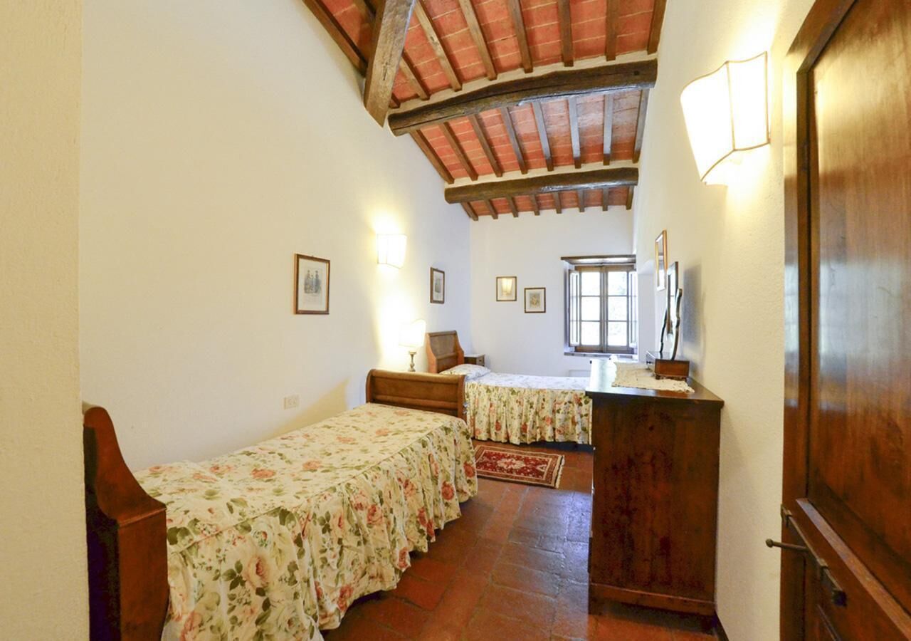 A bedroom with two single beds, a wooden dresser, and a window with a view.