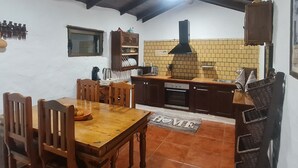 Una cocina acogedora con armarios de madera, salpicadero de azulejos y un comedor con mesa y sillas de madera.