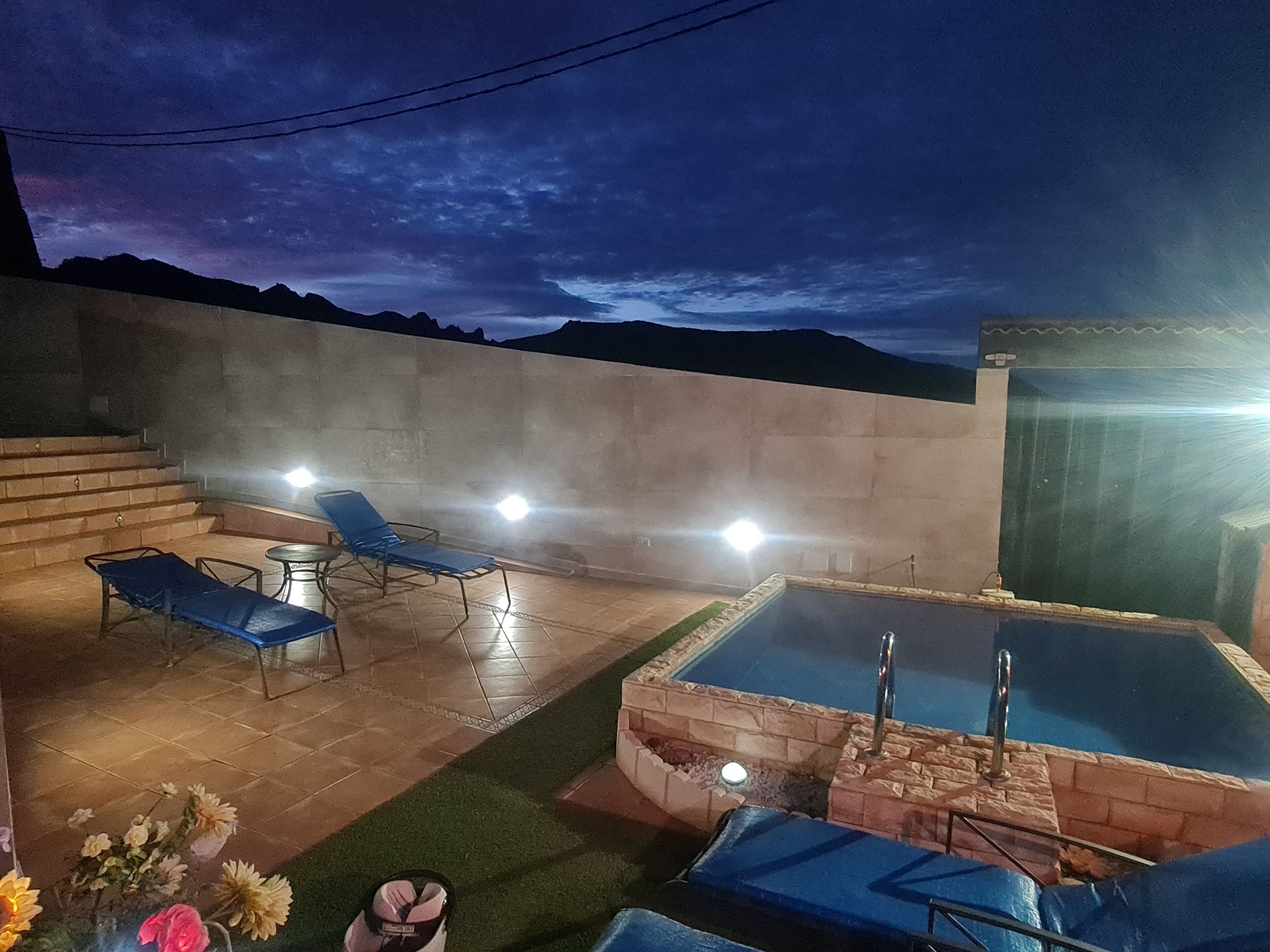 A rooftop pool area with a clear view of the mountains at dusk.