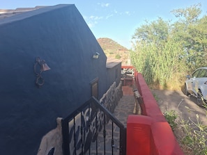 A narrow pathway leading to a building with a blue facade, a red wall, and a parked car. - Wonderful typical Canarian house with outdoor pool and wifi in the mountains. (Telde)