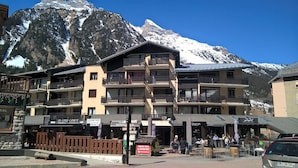 Un hotel de varios pisos con balcones, un restaurante y vistas a montañas nevadas.