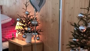 Una habitación acogedora con paredes de madera, un pequeño árbol de Navidad y un adorno con forma de corazón en un espejo.