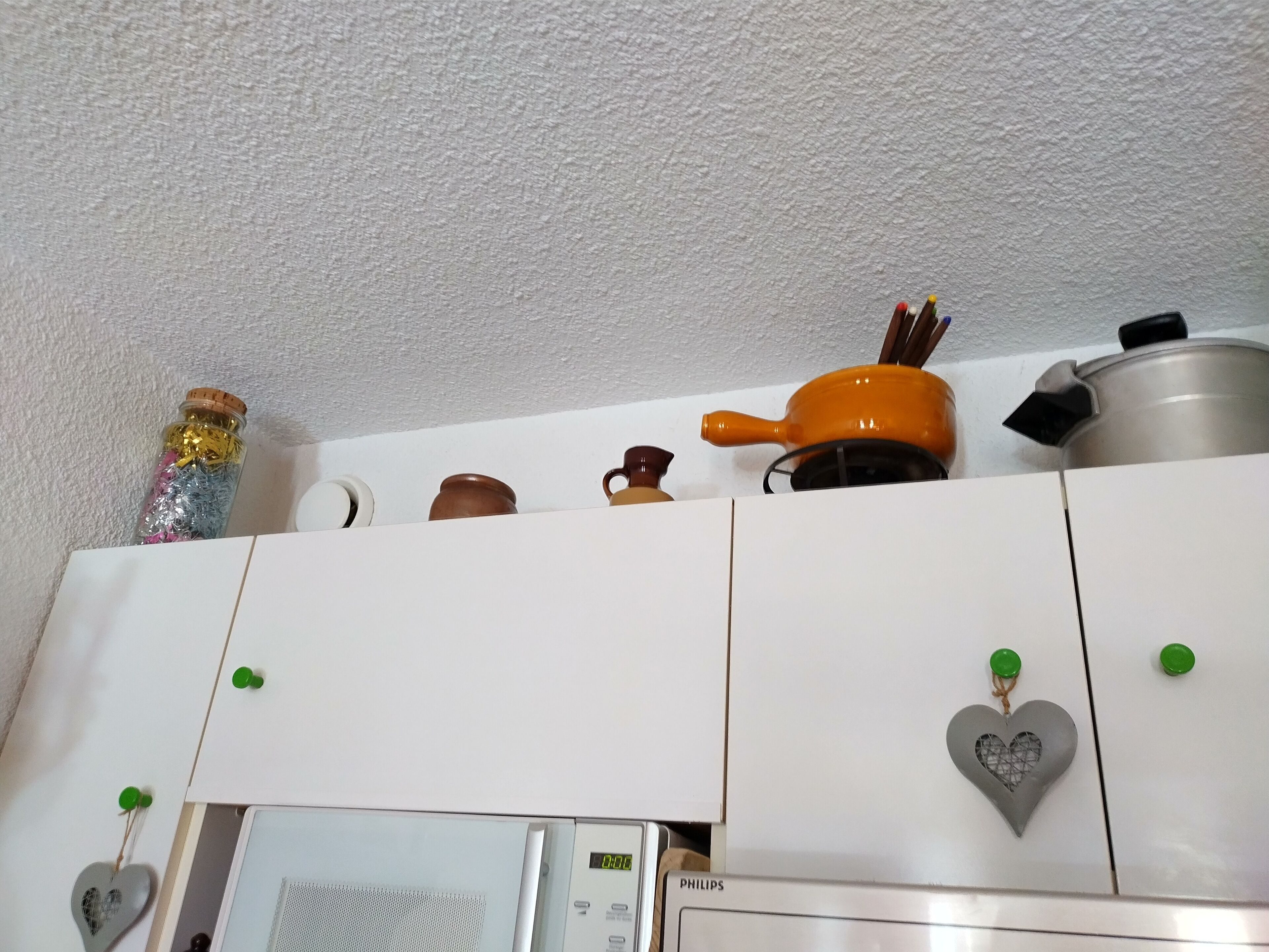 A kitchen with white cabinets, a microwave, and a heart-shaped decoration.