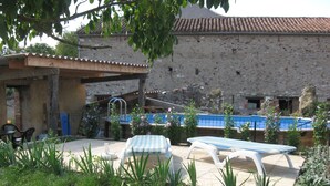 Ein Innenhof mit Pool, Sitzgelegenheiten im Freien und einem Steinhaus.