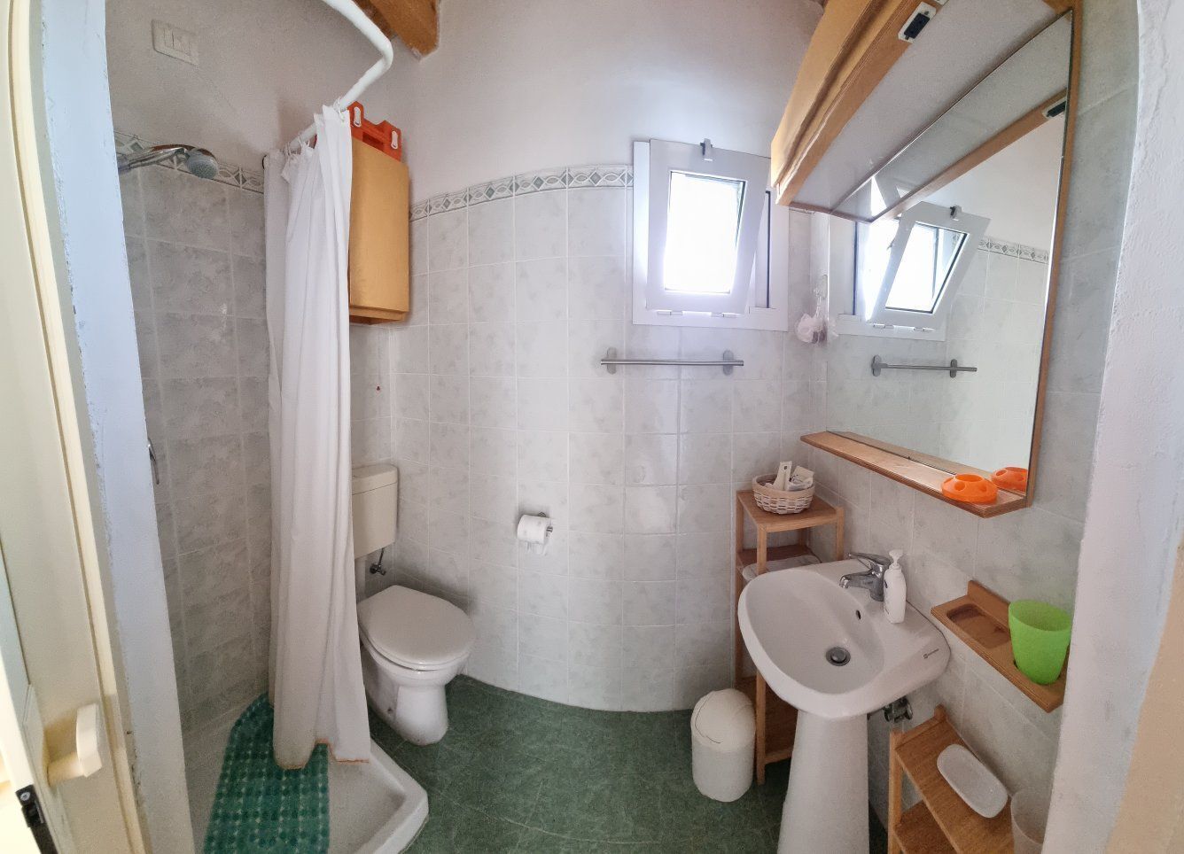 Een kleine badkamer met toilet, wastafel en douchehoek.