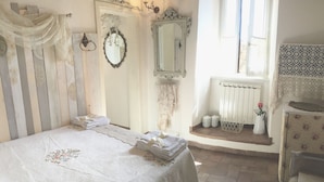 A bedroom with a bed, a mirror, a radiator, and a window with curtains.