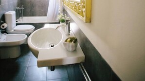 Een badkamer met een witte wastafel, toilet, bidet en bad.