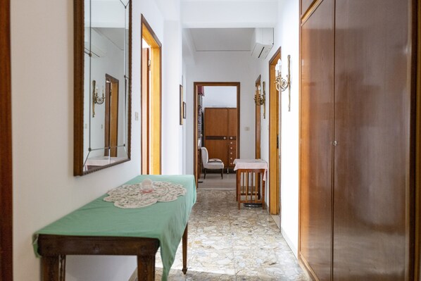 A narrow hallway with a wooden table and chairs, a mirror, and a wardrobe.