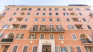 Un immeuble à plusieurs étages doté de balcons, d’une entrée principale et d’un panneau de signalisation bleu indiquant l’emplacement du parking.