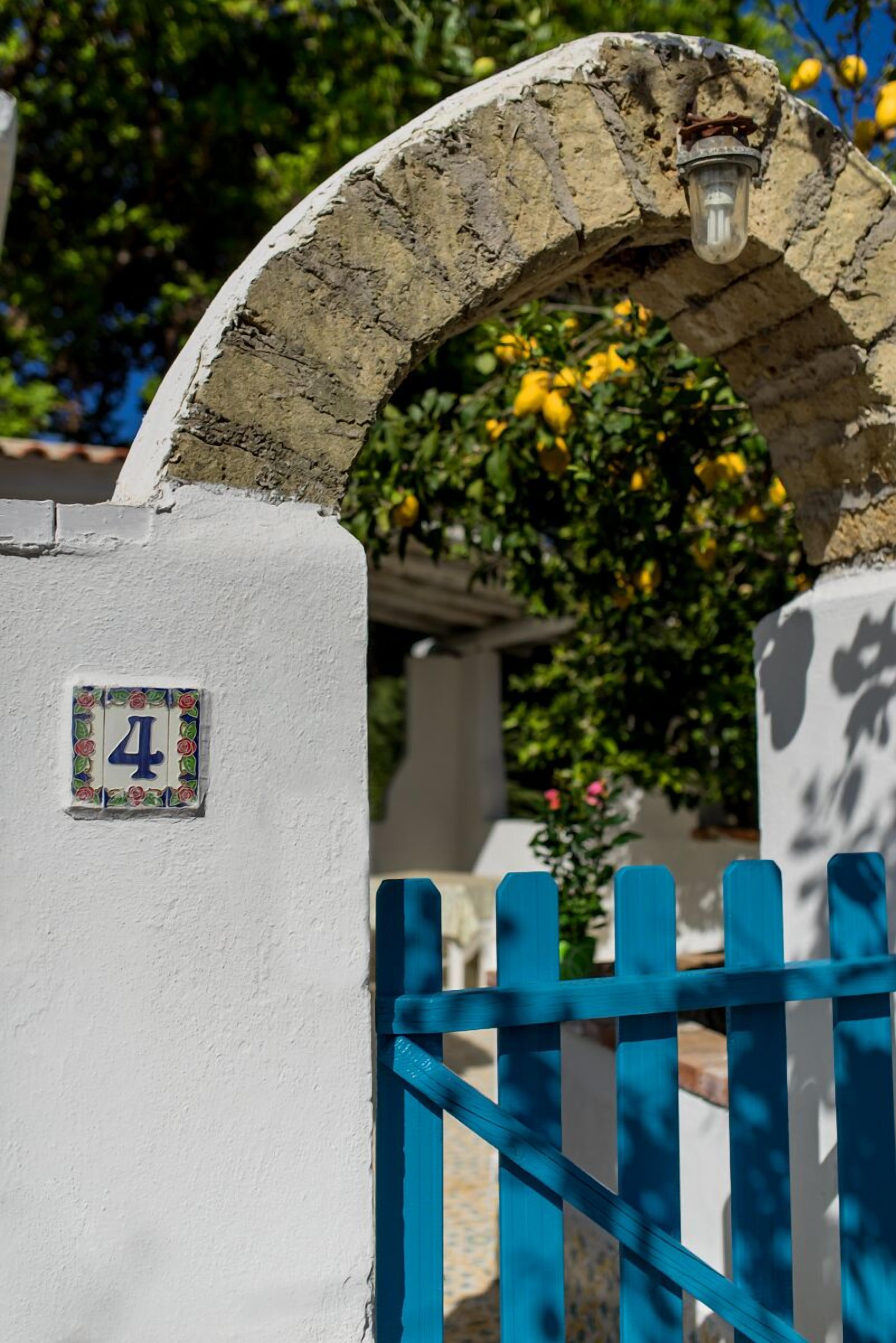Un mur blanc orné d’un panneau portant le chiffre « 4 », une porte bleue et une arche en pierre.