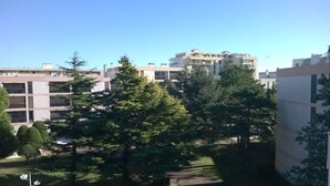 Un quartier résidentiel avec des immeubles modernes, une pelouse bien entretenue et un sentier menant à un banc.
