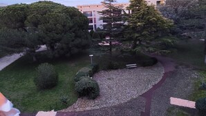 Un parc avec un sentier en pierre, des bancs et des arbres.