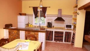 Una cucina compatta con zona pranzo, caratterizzata da un rivestimento in piastrelle, un forno a microonde e un piccolo frigorifero.