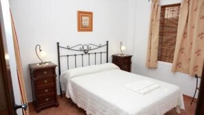 Una camera da letto con un letto singolo, un comodino, una cassettiera e una finestra con tende.