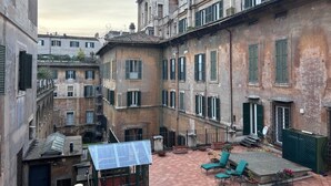 A courtyard with a solar panel, outdoor seating, and a building with multiple windows and balconies. - Rome: HISTORIC CENTER, close to the Pantheon, Trevi Fountain, Piazza di Spagna. (Roma)