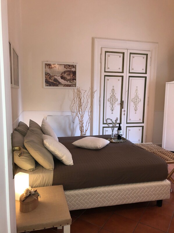Relax in a serene bedroom with a large bed, adorned with pillows and a bedside table, featuring a lamp and decorative vase.