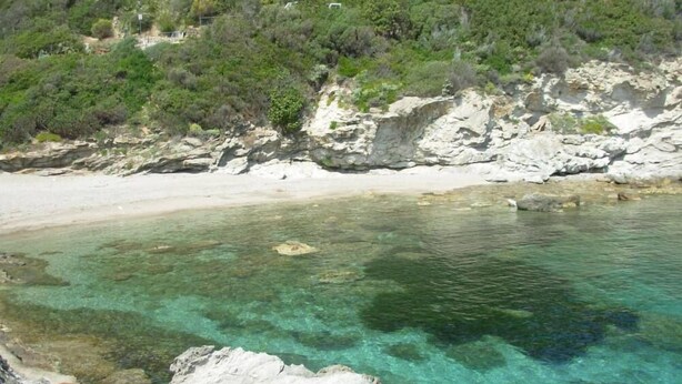 Un paysage côtier caractérisé par une eau turquoise et limpide, des rivages rocheux et une végétation luxuriante.