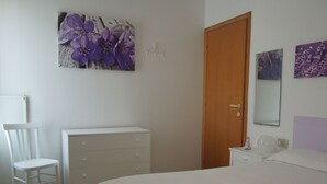 Une chambre à coucher avec un lit, une commode, une chaise et une porte.