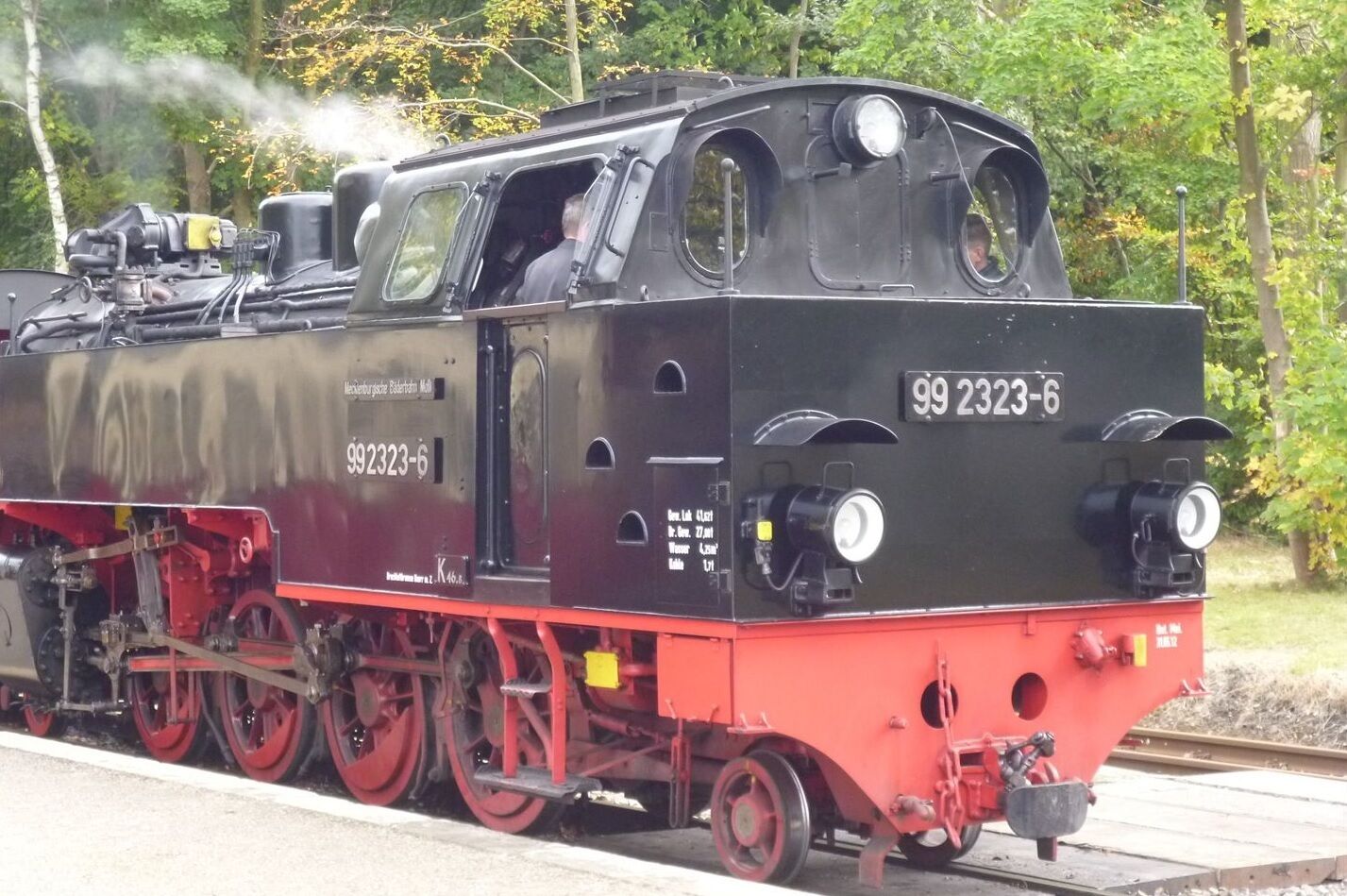 Una locomotora de vapor con el número 99 2323-6 sobre una vía férrea.