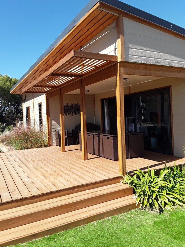 A modern house with a wooden deck, a covered patio, and a large window.