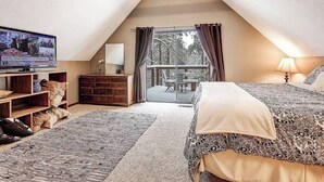 Un dormitorio acogedor en el ático con televisión, cómoda de madera y una cama grande.