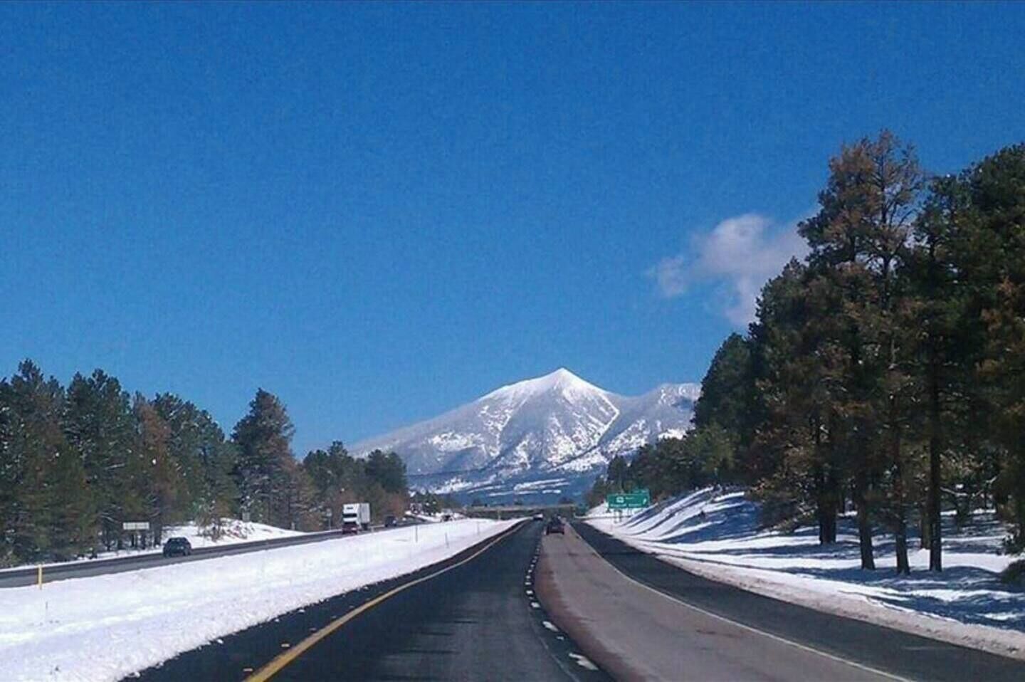 A road with a snow-covered landscape and a mountain in the distance.