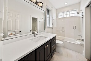 Een bad/douchecombinatie, een haardroger, handdoeken