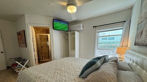 A bedroom with a bed, a TV mounted on the wall, a window with curtains, and a ceiling fan. -  ☀️Sunny Courtside House, 🏖STEPS TO OCEAN OR BAY, Bikes! South Mission BeachSD (San Diego)
