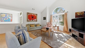 A modern living room with a sofa, armchair, coffee table, and TV. - Beautiful Home, Close to Beach, Lagoon, Fantastic Pool! (Hilton Head Island)