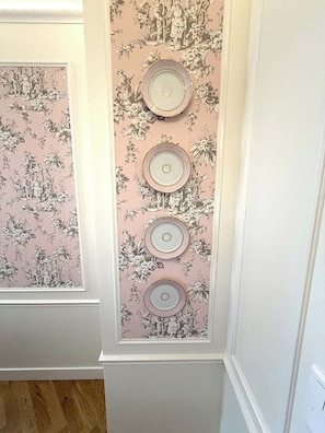 Paredes com papel de parede floral e uma série de objetos circulares.