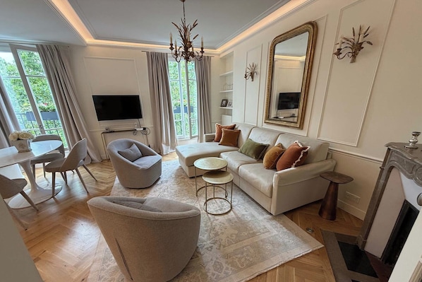 Uma sala de estar moderna com sofá, poltrona, televisão e objetos decorativos.
