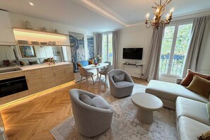 A modern living room with a sofa, armchairs, a coffee table, and a TV.