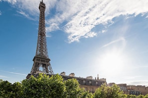 A Torre Eiffel com céu claro e edifícios ao redor.