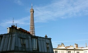 Une vue de la Tour Eiffel avec un bâtiment au premier plan.
