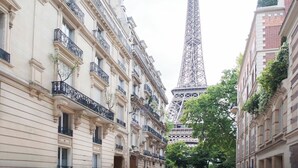 Une vue de rue avec la Tour Eiffel en arrière-plan, encadrée par des bâtiments représentatifs de l’architecture classique européenne.