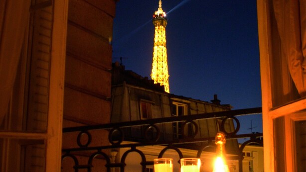Un balcon donnant sur une tour illuminée la nuit.
