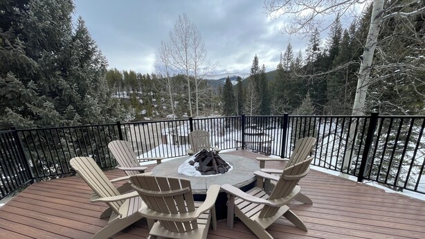 A deck with Adirondack chairs, a fire pit, and a view of a snowy landscape. - Ski-In, Ski-Out, Corner Unit. Sleeps 4. Hot Tubs, Pool, 65" OLED TV. Near Base (Winter Park)