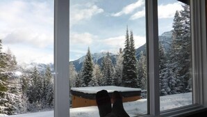 Una persona sentada junto a una ventana con vistas a árboles nevados y montañas.